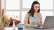 mujer sentada en un escritorio escribiendo en un portátil